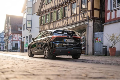 Rear view of a black car in front of historic half-timbered houses, captured in the evening mood,