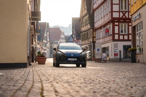 Black car in an inner city street with half-timbered houses, surrounded by a busy atmosphere in