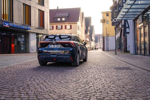 Black car on a paved street in the city with modern and historic architecture in the background at