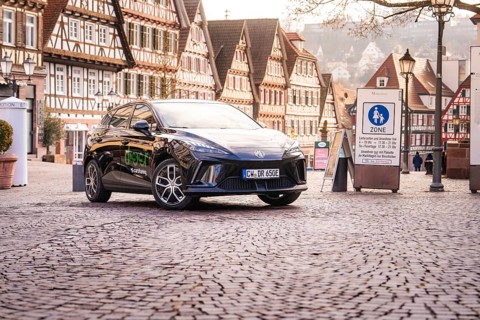 A car is parked in a historic old town with half-timbered houses and a charming atmosphere, MG4