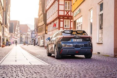 A black car on a sunny cobblestone street surrounded by half-timbered houses, MG4 electric car,