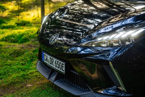 Close-up of front lights of a car with reflecting sunlight in the forest, MG4 electric car, Deer
