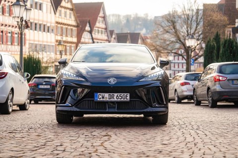 A car in an old town street with half-timbered houses and cobblestones, MG4 electric car, Deer