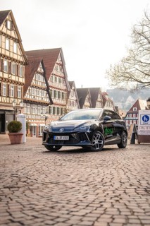 Car parked in a picturesque old town with half-timbered houses and paved streets, MG4 electric car,