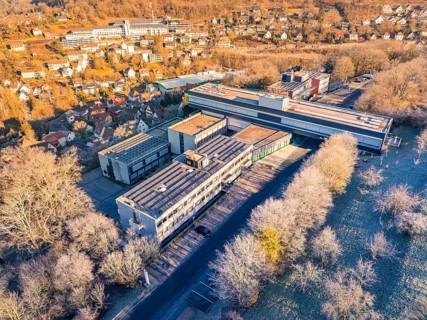 Aerial view of a large building complex surrounded by trees in an autumn landscape, MG4 electric