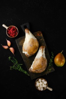Two duck legs poached in their own rendered fat served with pear, berries, garlic and thyme on a