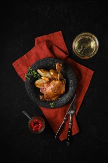 Top view of a plate with roasted duck leg along with caramelised pears and fresh thyme served with