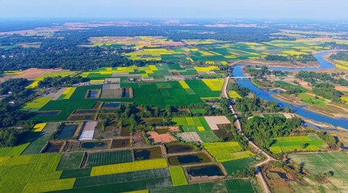An aerial view reveals a gently curving river winding through the countryside, its silvery surface