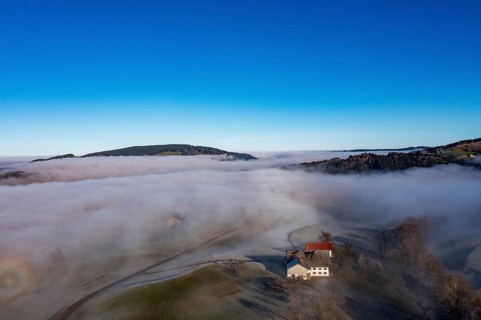 Drone view, agricultural landscape with farmhouse in autumnal morning fog, inversion weather,