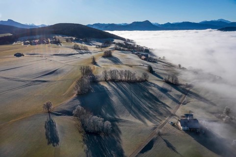 Drone view, agricultural landscape with farm in autumnal morning fog, inversion weather,