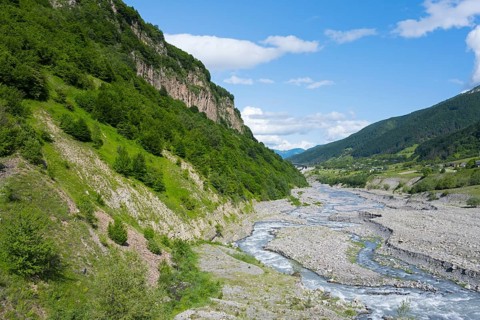 A river snakes through thick vegetation and steep cliffs, landscape near Kvemo Mleta, White Aragvi