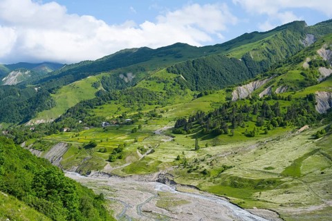 Wide green hills and a river criss-cross the mountainous landscape, landscape between Kvesheti and