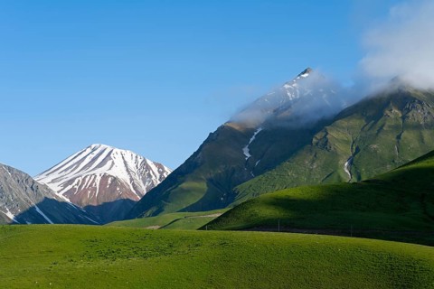 Hilly landscape with snow-capped peaks and clouds, landscape between Kvesheti and Gudauri,