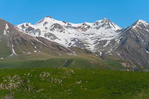 Impressive view of snow-capped mountains and green rocks, landscape between Kvesheti and Gudauri,