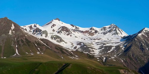 Snowy mountain peaks under a clear blue sky, landscape between Kvesheti and Gudauri,