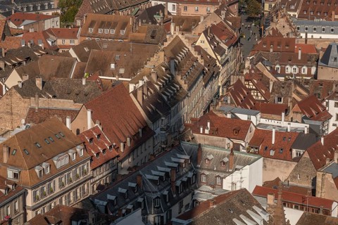The stone balcony offers a view of the city of Strasbourg. Houses and buildings can be seen under a