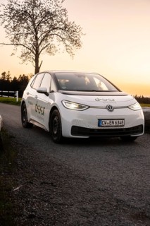 Car at sunset on street, parked with illuminated headlights, VW ID3 electric car, deer e-car