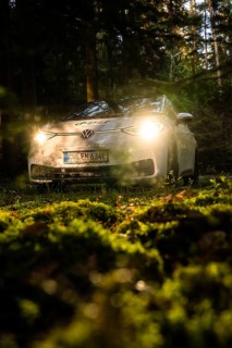 Car in the dark forest, headlights glow on mossy ground, mystical atmosphere, VW ID3 electric car,