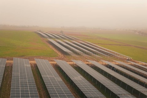 Rows of solar panels on vast green fields, focus on sustainability, energy transition, construction