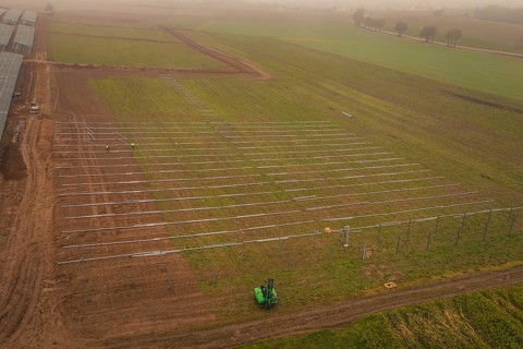 Foggy fields with solar system installation in the foreground, machines in use, energy revolution,