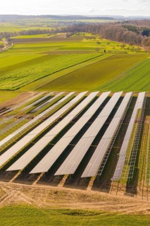 Aerial view of solar panels in an agricultural environment with vast green fields, energy