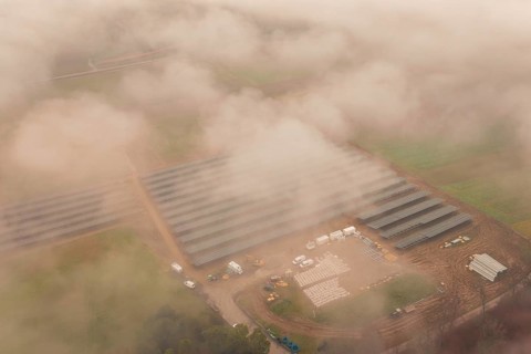 Construction site with solar systems in a foggy landscape, several vehicles visible, Energiewende,
