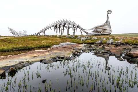 Wooden sculpture of a Viking ship and its reflection in a body of water, sculpture by Drakkar Vardø