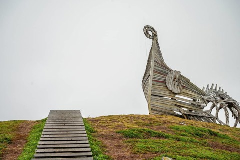 Wooden staircase leads to a sculptural wooden structure on a hill, sculpture by Drakkar Vardø. The