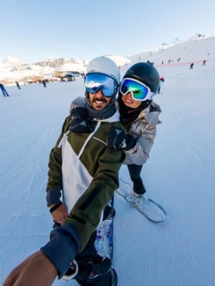 Couple having fun snowboarding on a sunny winter day, enjoying their active vacation in the snow