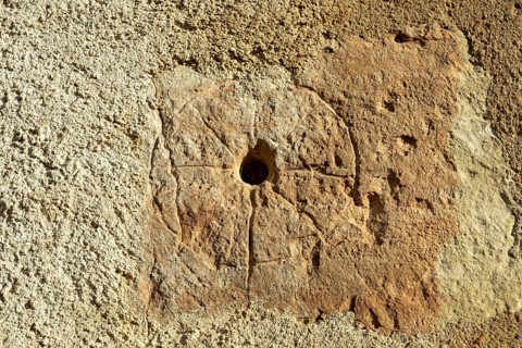 A close view showing a medieval mass dial carved into the exterior wall of St. Saturninus Church.