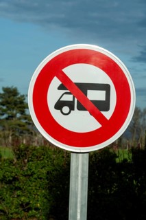 A round prohibition road sign forbids motorhomes. The sign is white with a red border and a red