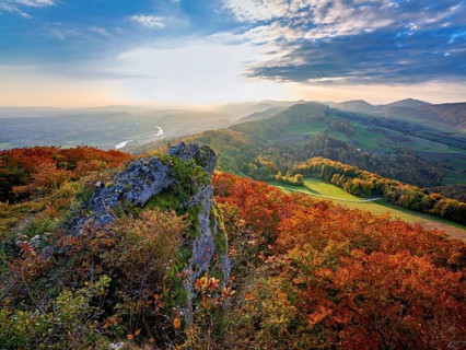 View of an autumnal forest from the Gisliflue, behind the Jura foothills with Wasserfluh and