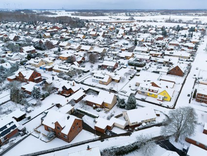 Snowy residential area with close-standing houses and snow-covered roads, aerial view, Oelsburg,
