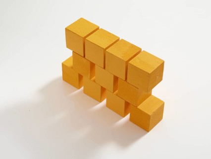 11 yellow wooden cubes against a white background
