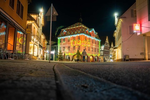 A lively cityscape at night with a brightly lit historic building and modest street lighting,