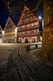 Beautiful half-timbered houses shine at night under fairy lights, captured by a curved wooden