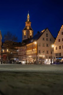 View of illuminated church tower and historic buildings in the evening darkness of the city,