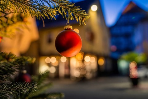 Red Christmas ball hanging on pine branch, blurred illuminated background, Nagold, Calw district,