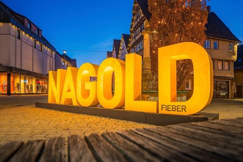Large illuminated lettering 'Nagold' in an evening city promenade, modern architecture, Nagold,