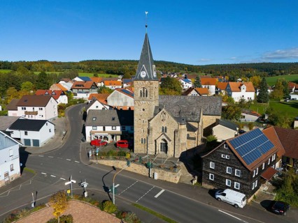 Close-up of a church in a village surrounded by roads and modern houses, aerial view,