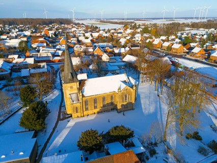 Snowy church in a village with a rural atmosphere, surrounded by wind turbines in a quiet winter