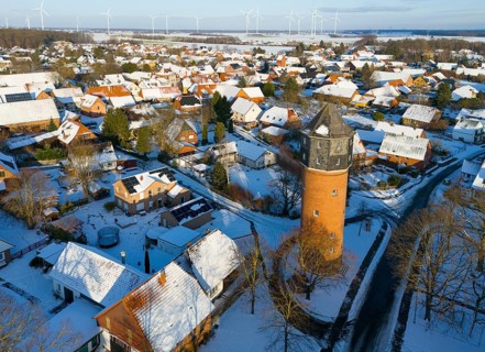 Winter village view with a distinctive water tower surrounded by snow-covered houses and distant