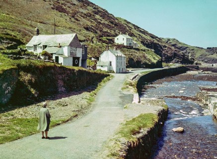 Road passing historic buildings by harbour wall fishing village of Boscastle, Cornwall, England, UK