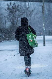 Winter weather, blowing snow, woman with e-scooter on snowy road, North Rhine-Westphalia, Germany
