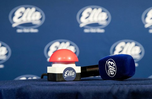The microphone and a buzzer are on the table in front of the red button is pressed at 12:00 and