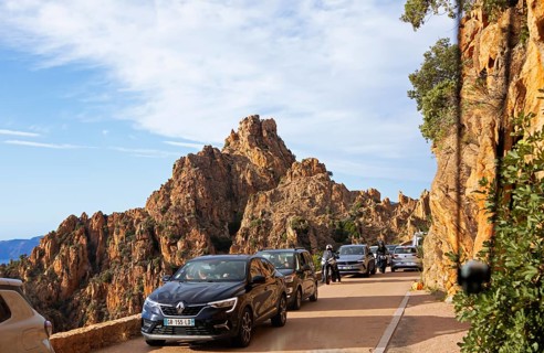 Bizarre rock erosion and car traffic, evening light, Calanche, Les Calanches de Piana,