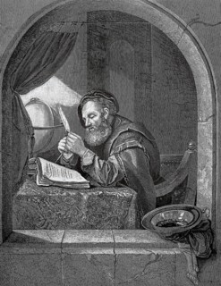 A scholar at his work desk in the 17th century, medieval man reading concentrated by lamplight at a