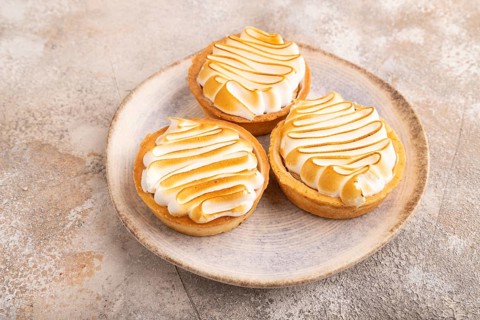 French lemon tart with meringue on brown concrete background, side view, close up