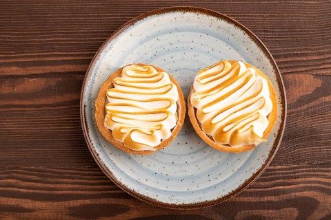 French lemon tart with meringue on brown wooden background, top view, flat lay, close up