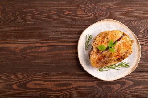 Fried Turkey Thigh with spices and rosemary on plate on brown wooden background. top view, flat